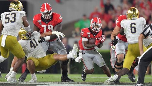 Georgia running back Brian Herrien (35) runs with the ball against Notre Dame, with Isaiah Wilson (79) blocking at Sanford Stadium in Athens on Saturday, Sept. 21, 2019. (Hyosub Shin / Hyosub.Shin@ajc.com)  **Isaiah Wilson (79 on left)**