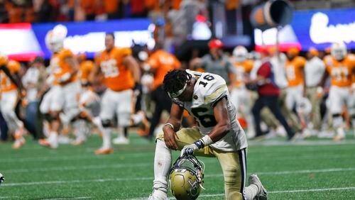 Georgia Tech quarterback TaQuon Marshall (16) kneels on the turf as Tennessee players rush the field after the second over time period of an NCAA college football game Tuesday, Sept. 5, 2017, in Atlanta. Tennessee won 42-41. (AP Photo/John Bazemore)