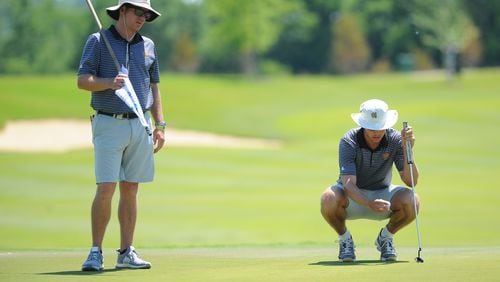 Kennesaw State golf coach Bryant Odom minds the flag while sophomore Jake Fendt considers his putt at the NCAA regional. (Tim Cowie/Kennesaw State)