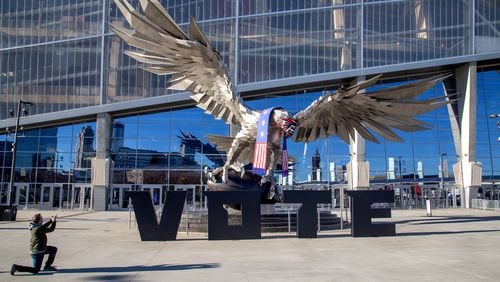 Philip Hourouras takes a photo of the falcon in front of the Mercedes-Benz Stadium on the first day of Early Voting at the Stadium Tuesday, December 22, 2020.  STEVE SCHAEFER FOR THE ATLANTA JOURNAL-CONSTITUTION
