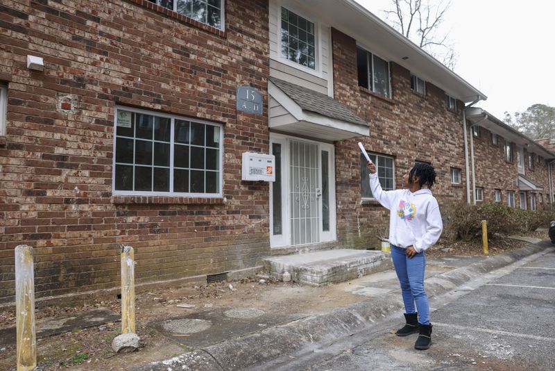 In February, Danielle Russell points out empty units in her building at Pavilion Place apartments that remained in disrepair more than a year after an October 2021 fire. Repairs were still unfinished this summer. (Jason Getz/Jason.Getz@ajc.com)
