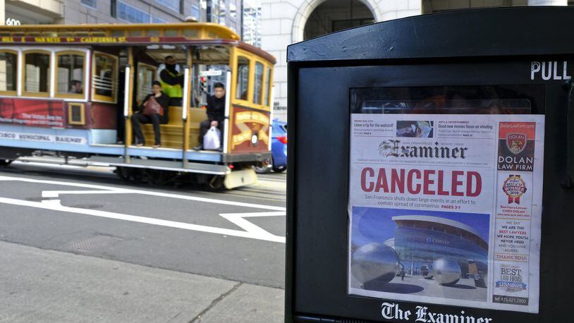 A newspaper headline announcing the closure of large events is displayed Friday, March 13, 2020, in San Francisco. A wave of closures and postponements spanning everything from government offices to cultural events and sports followed concerns of the coronavirus’ spread. (AP Photo/Eric Risberg)