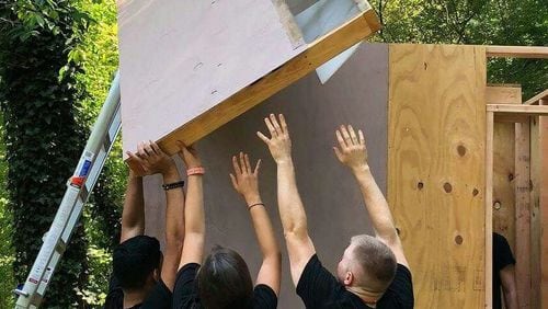 During a recent build, volunteers are shown raising a panel for one of the homes.
