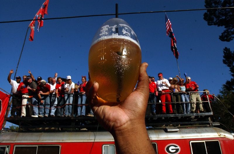 JACKSONVILLE, FL -- A fan holds up the beverage of choice before the game Saturday afternoon November 2, 2002 in front of a UGA fan bus. Fans came to the stadium several hours before the game to enjoy the festivities known as the 'biggest outdoor cocktail party.' (Rich Addicks/AJC Staff)