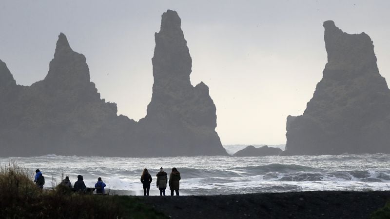 FILE - In this Oct. 26, 2016 file photo, people walk on the black sanded beach in Vik, Iceland, near the Volcano Katla. After a summer of increased seismic activity at Katla, Icelanders are obsessing over the smallest sign of an eruption at the countryâs most closely watched volcano. Katla last erupted in 1918. Never before in recorded history, dating back to the 12th century, have 99 years passed without an eruption from the volcano. (AP Photo/Frank Augstein, File)