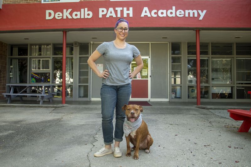 DeKalb PATH Academy fifth grade science teacher Tiffany Lester stands for a portrait with her dog, Gary Fishlegs, who is also the school's registered therapy dog, outside of the school in Brookhaven on August 13. (ALYSSA POINTER / ALYSSA.POINTER@AJC.COM)