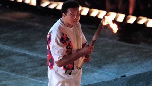Muhammad Ali lights the torch to launch the 1996 Olympics in Atlanta. Illustrations from an Ali biography are on display at the Auburn Avenue Research Library (AJC file photo)