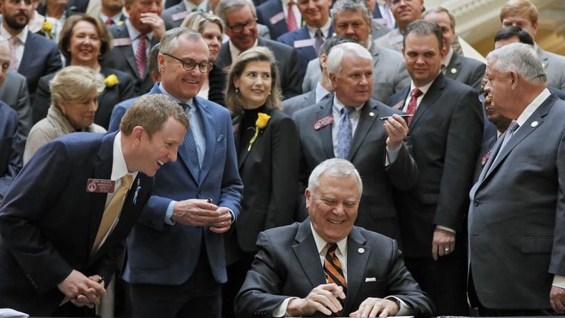 State Rep. Bert Reeves, R-Marietta, Lt. Gov. Casey Cagle, House Speaker David Ralston and other lawmakers watch as Gov. Nathan Deal signs into law the adoption bill Reeves authored. BOB ANDRES /BANDRES@AJC.COM