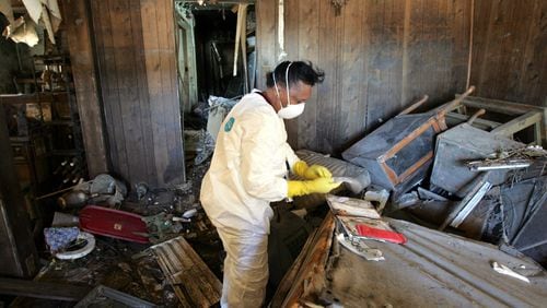 Brenda Slack, who moved to Clayton County after Hurricane Katrina, is shown here in 2006 wearing a protective suit to protect her from mold as she recovers items from her former home in the Lower 9th Ward of New Orleans. (PHOTO by Brant Sanderlin photo/ AJC Staff)