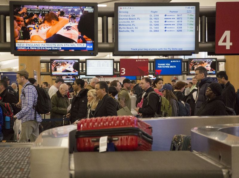 Luggage comes off the suitcases come off conveyer belts as multiple security lines at Hartsfield-Jackson International Airport snaked through baggage claim then the atrium in both domestic terminals on Monday February 4th, 2019. Official expected over 100,00 travelers to pass through the airport today. (Photo by Phil Skinner)
