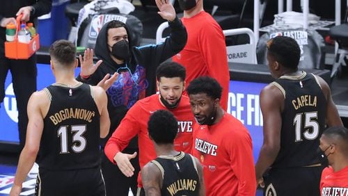 Hawks' injured guard Trae Young gives teammates high fives as they take the early lead against the Milwaukee Bucks during the first quarter of Game 4 of the Eastern Conference finals Tuesday, June 29, 2021, at State Farm Arena in Atlanta. (Curtis Compton / Curtis.Compton@ajc.com)