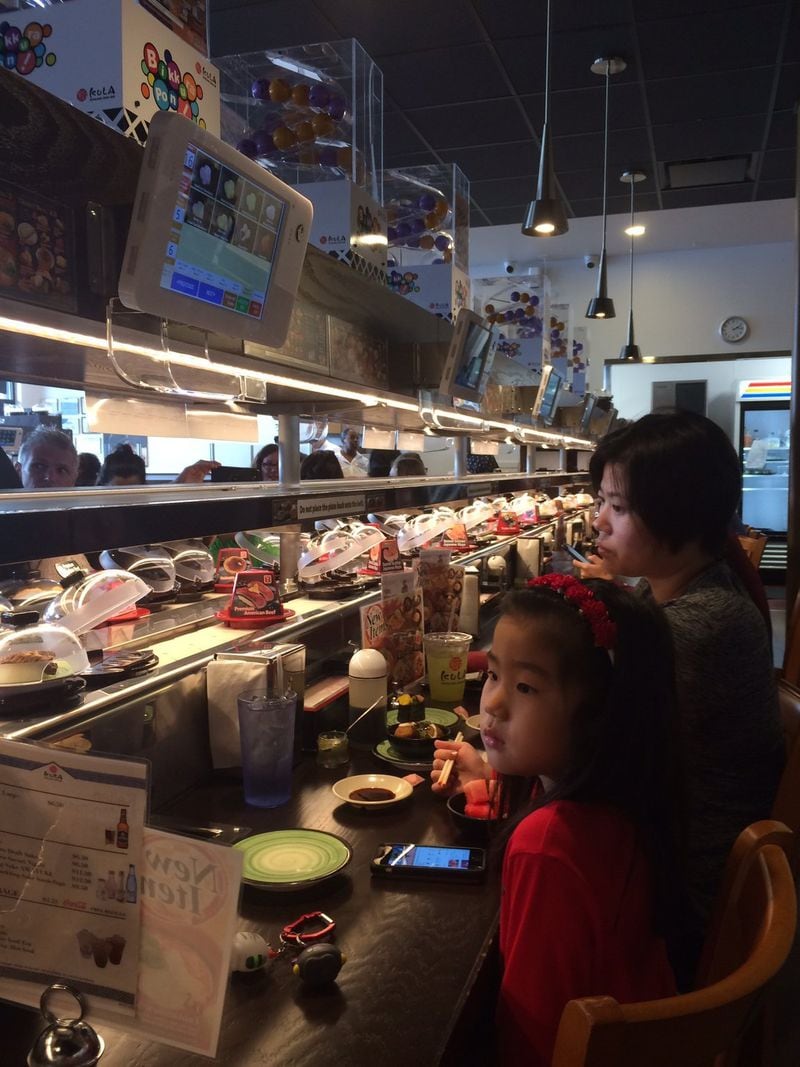 Customers check out the offerings at Kura Revolving Sushi Bar in 2017. AJC FILE/CONTRIBUTED BY WENDELL BROCK