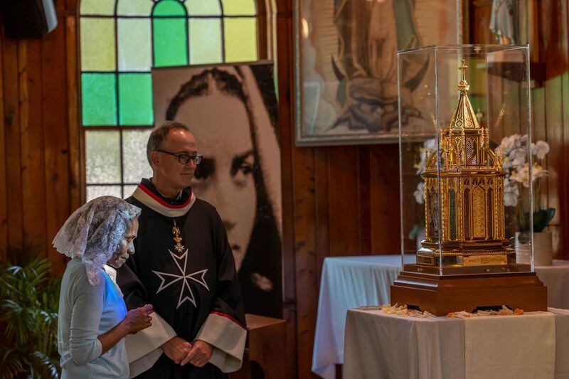A parishioner pauses for a prayer near the relics of St. Bernadette as a member of the Knights of Malta looks on during a visit to Our Lady of Lourdes Catholic Church in Port Wentworth.