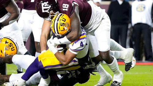 LSU running back John Emery Jr. (4) drags Texas A&M defensive lineman LT Overton (18) across the goal line for a touchdown during the first half of an NCAA college football game Saturday, Nov. 26, 2022, in College Station, Texas. (AP Photo/Sam Craft)
