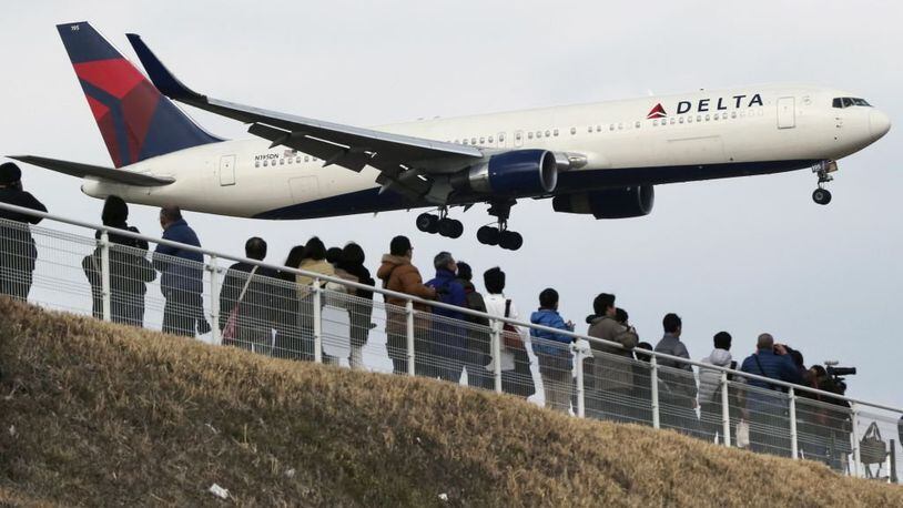 People watch as a Delta Air Lines jet lands at Narita Airport, about an hour east of central Tokyo.