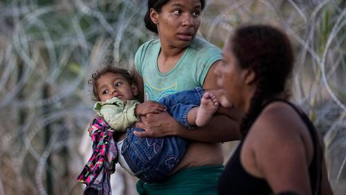 A woman carries her child after she and other migrants crossed the Rio Grande and entered the U.S. from Mexico, to be processed by U.S. Customs and Border Protection, Saturday, Sept. 23, 2023, in Eagle Pass, Texas. The image was part of a series by Associated Press photographers Ivan Valencia, Eduardo Verdugo, Felix Marquez, Marco Ugarte Fernando Llano, Eric Gay, Gregory Bull and Christian Chavez that won the 2024 Pulitzer Prize for feature photography. (AP Photo/Eric Gay)