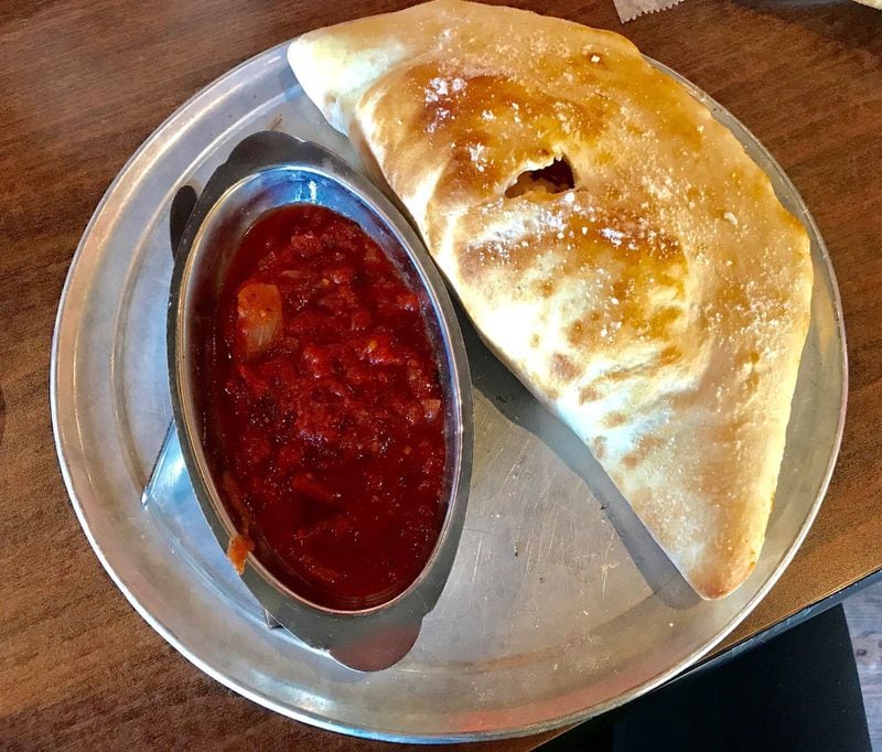 The calzone at Oz Pizza is already something great to behold, and the marinara sauce just makes it better. LIGAYA FIGUERAS / LFIGUERAS@AJC.COM