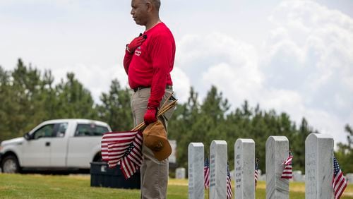 Marine veteran Maurice Hurst pays respects after placing an American flag near a headstone at the Georgia National Cemetery in Canton during Memorial Day in 2021. (AJC FILE)