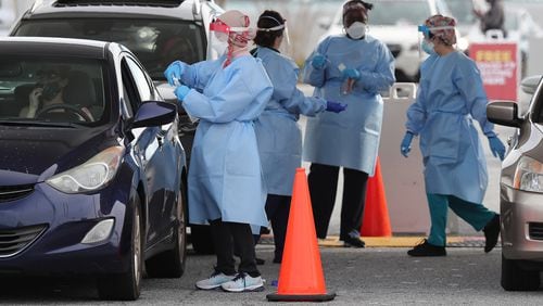122320 Doraville: RN Elham Roshanraun (left) and other nurses work a line of motorists at a free drive through COVID-19 DeKalb Board of Health testing site located by the Brandsmart USA while coronavirus testing surges as Christmas nears on Wednesday, Dec. 23, 2020, in Doraville.  “Curtis Compton / Curtis.Compton@ajc.com”