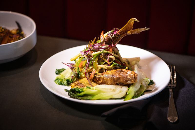 A dish that shows chef Scotley Innis mixing worldwide influences is the Continent's Fried Whole Snapper with red coconut curry sauce and Szechuan vegetables. Mia Yakel for The AJC
