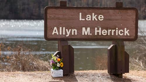 Family members laid flowers at the Lake Allyn M. Herrick sign in Athens at the University of Georgia on Friday, Feb. 23, 2024. Laken Riley, a 22-year-old, nursing student was found dead nearby on Thursday. (Jason Getz / jason.getz@ajc.com)
