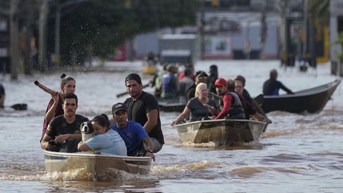 Volunteers help to evacuate residents from an area flooded by heavy rains, in Porto Alegre, Brazil, Tuesday, May 7, 2024. (AP Photo/Andre Penner)