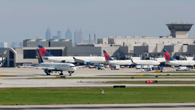 With the Atlanta skyline in the background, a Delta airplane taxis at Hartsfield-Jackson International Airport on Wednesday. An ambitious plan to expand the airport has grown to $11.5 billion in projects and now extends through 2042. (Jason Getz / Jason.Getz@ajc.com)