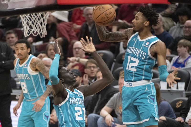 Charlotte Hornets' Leaky Black (12) grabs a rebound as teammate JT Thor (21) looks on during the first half of an NBA basketball game against the Cleveland Cavaliers in Cleveland, Sunday, April 14, 2024. (AP Photo/Phil Long)