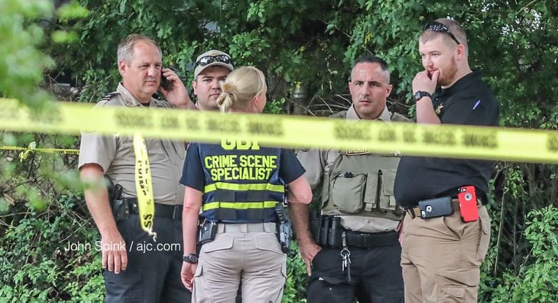 A GBI investigator speaks with Hall County sheriff's deputies on the scene of a deadly deputy-involved shooting Thursday morning. JOHN SPINK / JSPINK@AJC.COM