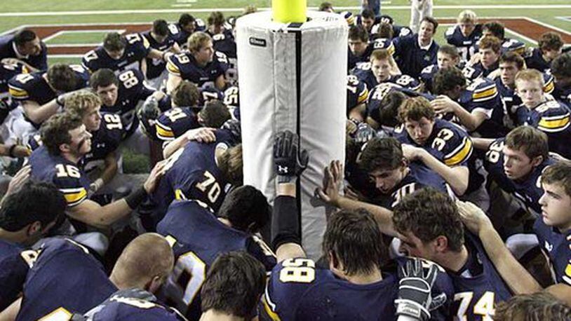 The Marist football team gathers around the goal post to pray before they run through the banner to start their 2008 Class AAAA state final versus Tucker at the Georgia Dome.