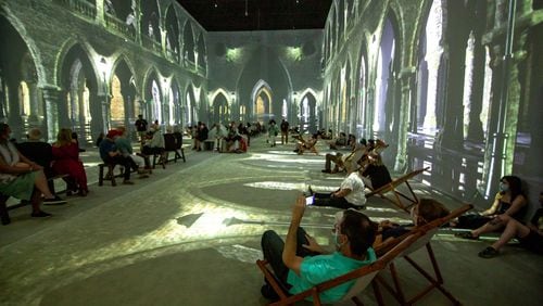 People sit and watch the four-story animated projections during the exhibit, "Van Gogh: The Immersive Experience" at the Pratt-Pullman Yard in Atlanta. STEVE SCHAEFER FOR THE ATLANTA JOURNAL-CONSTITUTION