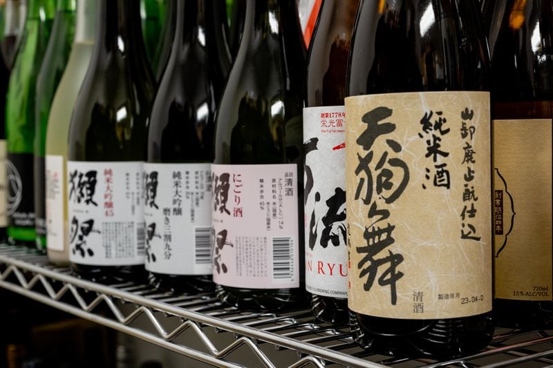 Bottles of sake sit in a special storage area at Brush Sushi. On the restaurant's menu, Allen has created a helpful chart that illustrates different sake flavor profiles. (Jason Allen/Atlanta Journal-Constitution)