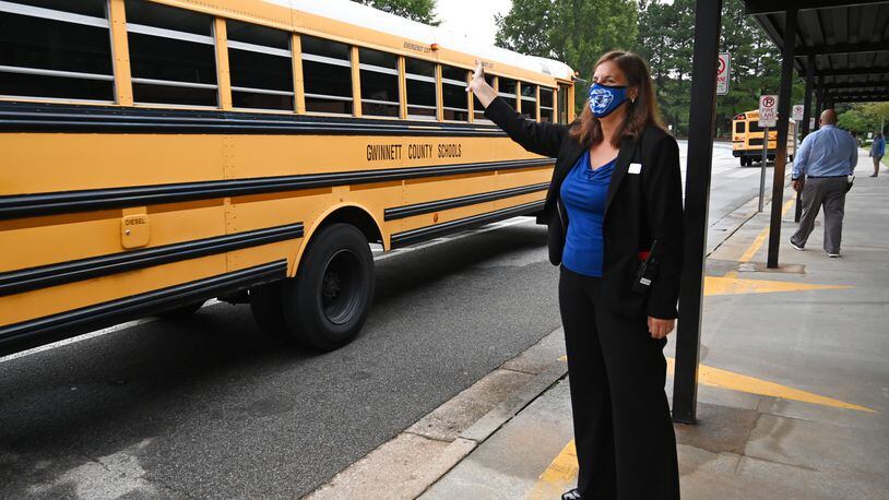 Kara Dutton, principal, waves as school buses arrive at Jackson Elementary School in Lawrenceville on the first day of school for younger students amid the coronavirus outbreak on Wednesday, Aug. 26, 2020. Gwinnett County Public Schools does report  COVID-19 cases by school on its website. Hyosub Shin / Hyosub.Shin@ajc.com