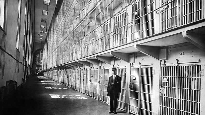A guard at the Reformatory is photographed in 1911 with the tiers of cell blocks shown over his head and the cavernous prison stretching out behind him. 