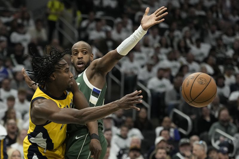 Indiana Pacers' Aaron Nesmith passes around Milwaukee Bucks' Khris Middleton during the second half of Game 2 of the first round NBA playoff basketball series Tuesday, April 23, 2024, in Milwaukee.The Pacers won 125-108 to tie the series 1-1. (AP Photo/Morry Gash)