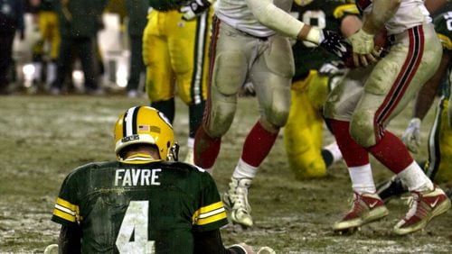 Packers quarterback Brett Favre sits dejected in the snow as Falcons defensive ends Brady Smith (center) and Patrick Kerney come up with his fumble celebrating during 4th quarter. (Curtis Compton/AJC)