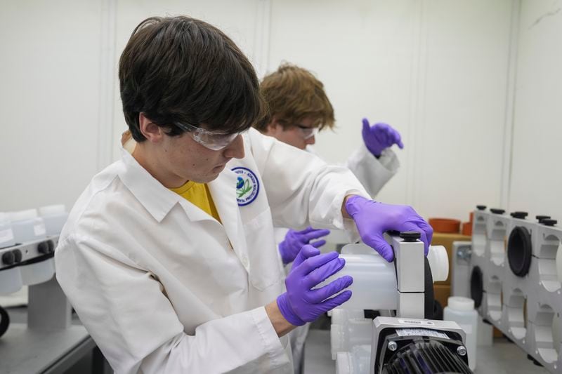 Jackson Quinn, foreground, places a bottle contains a PFAS water sample into a rotator, Wednesday, April 10, 2024, at a U.S. Environmental Protection Agency lab in Cincinnati. The Environmental Protection Agency on Wednesday announced its first-ever limits for several common types of PFAS, the so-called "forever chemicals," in drinking water. (AP Photo/Joshua A. Bickel)
