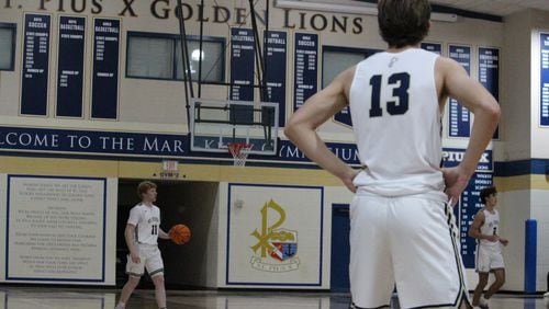 Brooks Kahlert brings the ball up the court for St. Pius while teammate Daniel Beverly (No. 13) awaits.
