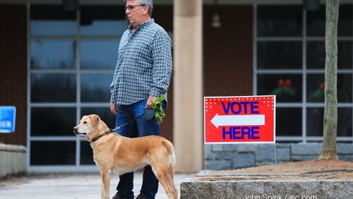 Harold Duvall gets pleasant weather Tuesday morning as he waits with his dog Riley for his wife to vote at Grady High School. But wet weather is on the way.