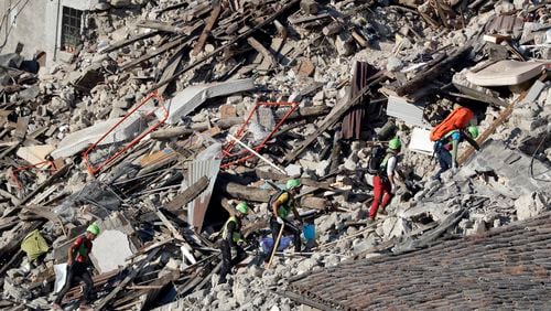 Rescuers make their way through destroyed houses following an earthquake in Pescara Del Tronto, central Italy, Thursday, Aug. 25, 2016. The magnitude 6 quake struck Wednesday at 3:36 a.m. (0136 GMT) and was felt across a broad swath of central Italy, including Rome where residents of the capital felt a long swaying followed by aftershocks. (AP Photo/Gregorio Borgia)