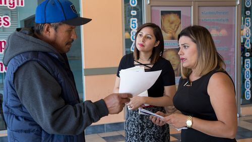 Navigators Viviana Cossio, center, and Carolina Montilla talk to a shopper Saturday at the Santa Fe Mall in Duluth about enrolling for health insurance under the Affordable Care Act, also known as Obamacare. This year’s federal grant for ACA navigators went to Georgia Refugee Health and Mental Health, which created Obamacare Para Latinos for Spanish speakers and HealthcareGA for English speakers. (PHOTO by STEVE SCHAEFER / SPECIAL TO THE AJC)