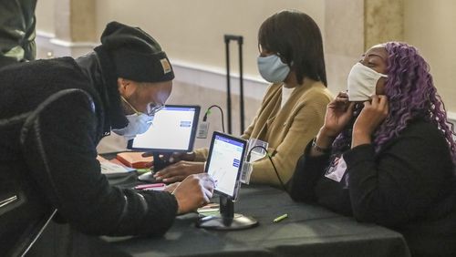 January 5, 2021 Atlanta: Kamal Gillespie (left) verifies his voter I.D. information to poll workers Brandy Allen (center) and Cuedriene Edwards (right) on Tuesday, Jan. 5, 2021 at the Park Tavern located at 500 10th St NE in Atlanta. Georgia’s long moment in the national spotlight culminated Tuesday, Jan. 5, 2021, when state voters cast their votes to determine which party would control the U.S. Senate. Georgia voters also voted to elect a member of the state Public Service Commission, which regulates energy and utility rates and issues. The two most expensive Senate races in history saw more than $833 million been spent by the four campaigns and outside groups supporting them, blanketing the airwaves and stuffing mailboxes across the state. Much of that money has come from organizations with no direct connection to Georgia. (John Spink / John.Spink@ajc.com)

