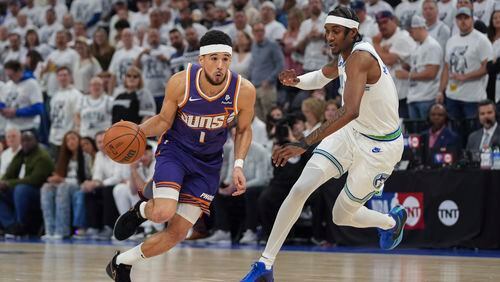 Phoenix Suns guard Devin Booker (1) drives against Minnesota Timberwolves forward Jaden McDaniels during the first half of Game 2 of an NBA basketball first-round playoff series Tuesday, April 23, 2024, in Minneapolis. (AP Photo/Abbie Parr)
