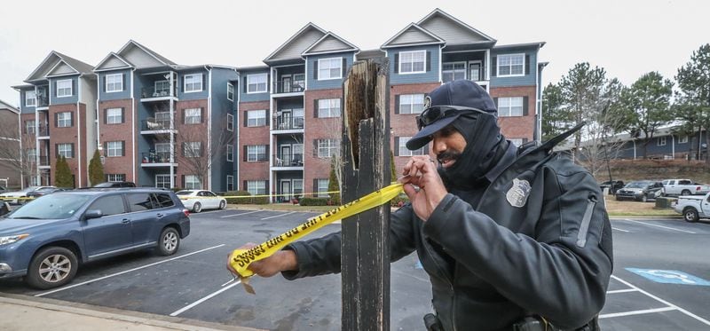 An Atlanta police officer tapes off the scene of a shooting at the Castleton Apartments. 