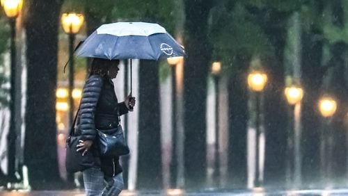 A woman crosses the intersection at West Peachtree and 15th streets as rain fell Tuesday morning.