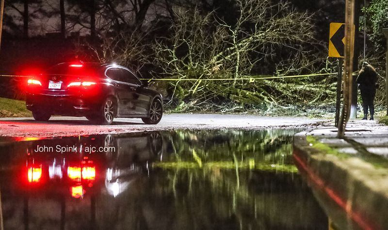 Heavy rain moved through metro Atlanta overnight Wednesday, causing some minor flooding and downed trees. One fallen tree was blocking Howell Mill Road at Margaret Mitchell Road on Thursday morning. JOHN SPINK / JSPINK@AJC.COM