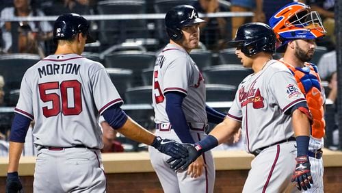 Atlanta Braves' Austin Riley, right front, celebrates with Charlie Morton (50) and Freddie Freeman (5) after they scored on Riley's grand slam during the fourth inning of the team's baseball game against the New York Mets, Tuesday, July 27, 2021, in New York. (AP Photo/Mary Altaffer)