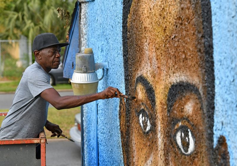 Miami based artist Marvin Weeks, who is originally from Brunswick, works on a large mural in tribute to Ahmaud Arbery on the side of a building which will soon be the site of the Brunswick African American Cultural Center in Brunswick. AJC photo: Hyosub Shin