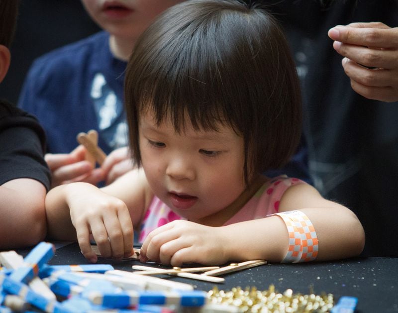 Anna Pena, 2,  works on assembling a robot arm she is constructing from Popsicle sticks during Robots Day at the Fernbank Museum of Natural History on Saturday, June 23, 2018. (STEVE SCHAEFER / SPECIAL TO THE AJC)