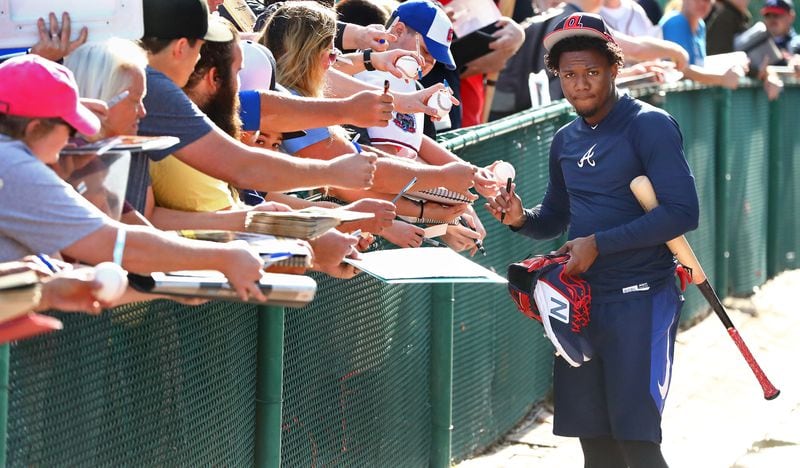 Braves fans work the fence line while outfielder Ronald Acuna pauses to sign some autographs leaving the batting cages during the first workout of spring training Feb. 16, 2019, at the ESPN Wide World of Sports Complex in Lake Buena Vista, Fla. (Curtis Compton/ccompton@ajc.com)